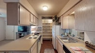 Located at 922 N Sidney Ave in Russellville, Arkansas, this single-floor residence offers a well-organized layout that makes efficient use of its space throughout. The galley-style kitchen is thoughtfully designed with ample light wood cabinetry on both sides, laminate countertops, a double-coil electric range, a dishwasher, and a stainless steel sink. A built-in open shelving pantry at the end of the kitchen provides generous storage, while wood-look flooring adds warmth underfoot. The living room is bright and inviting, featuring large windows that allow natural light to fill the carpeted space, complemented by a textured ceiling. Two well-proportioned bedrooms each feature ceiling fans with light fixtures, soft carpet flooring, textured ceilings, and windows that bring in natural light. The full bathroom is finished with wood-look flooring, a vanity with cabinetry, a combined tub and shower enclosed with a sliding glass door, and a toilet. A notable convenience is the in-unit laundry area, which accommodates a full-size washer and dryer stacked adjacent to the bathroom. Throughout the residence, neutral tones and textured ceilings create a cohesive, comfortable ambiance suitable for everyday living.