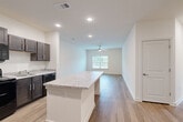 This single-floor, 2-bedroom, 1-bathroom residence offers a thoughtfully designed layout with modern finishes throughout. The open-concept kitchen and living area serves as the heart of the home, anchored by a central granite-topped island that provides both additional prep space and a natural gathering point. The kitchen features dark espresso cabinetry, granite countertops, black appliances including a refrigerator, range, and dishwasher, and is illuminated by recessed lighting. The space flows seamlessly into the living area, which is fitted with wood-style plank flooring, a ceiling fan, and a window that brings in natural light and outdoor views. Both bedrooms are comfortably sized, with the primary bedroom offering wood-style flooring and a ceiling fan, while the second bedroom features plush carpeting and access to a closet. The shared bathroom is clean and functional, equipped with a granite-topped vanity with dark wood cabinetry, a framed mirror, and a full tub/shower combo with brushed nickel fixtures. Neutral wall tones, clean white trim, and consistent flooring choices throughout the home create a cohesive, modern aesthetic that is move-in ready.