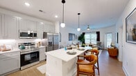 Located in Hendersonville, NC, this thoughtfully designed one-bedroom, one-bathroom residence offers a cohesive and modern living experience across a single floor. The open-concept layout seamlessly connects the kitchen and living room, creating a bright and airy atmosphere ideal for both everyday living and entertaining. The kitchen is outfitted with gray shaker-style cabinetry, white quartz countertops, a tiled backsplash, stainless steel appliances—including a French door refrigerator, range, and microwave—and a central island with pendant lighting and bar seating. The living area features light wood-style flooring, a ceiling fan, and large windows that invite an abundance of natural light, with a door opening directly onto the private balcony. The bedroom is a comfortable retreat with a ceiling fan, large windows, and convenient access to a walk-in closet. The bathroom is finished with a white vanity with quartz countertop, a framed mirror, and a full soaking tub with shower. Additional highlights include in-unit laundry, four closets for generous storage, and a welcoming entry foyer with an arched mirror. The clean, neutral palette throughout lends a fresh and timeless feel to the entire space.