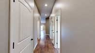 Located at 7901 SW 7th St in Blue Springs, MO, this single-story, 3-bedroom, 2-bathroom home offers a thoughtfully designed layout with quality finishes throughout. The open-concept living room features vaulted ceilings, rich hardwood-style flooring, a ceiling fan, and a sliding glass door that fills the space with natural light and provides direct outdoor access. The kitchen is well-equipped with warm oak cabinetry, granite-look countertops, a tile backsplash, black appliances, and a central island with breakfast bar seating — all complemented by matching hardwood-style flooring. The spacious primary bedroom showcases a tray ceiling with a ceiling fan, plush carpeting, and dual windows that invite natural light. It is accompanied by a dedicated bathroom featuring a walk-in glass-door shower and a vanity with an oil-rubbed bronze faucet. The two additional bedrooms are carpeted and include closet storage and windows overlooking the surroundings. A second full bathroom with a vanity and large mirror serves the remaining bedrooms. A hallway connects all rooms efficiently, rounding out this comfortable and practical single-floor home.