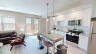 This 640 square foot one-bedroom apartment offers a thoughtfully designed living space on a single floor. The open-concept layout seamlessly integrates the kitchen, living, and dining areas, creating a sense of spaciousness. The modern kitchen boasts white cabinetry, stainless steel appliances, and a granite-topped island with seating.

The living area is flooded with natural light from large windows and features contemporary furnishings and a mounted TV. Ceiling fans throughout enhance air circulation and comfort. The bedroom, measuring 130 square feet, includes a walk-in closet with ample storage solutions.

The bathroom showcases a sleek design with a glass-enclosed shower, marble-like tiling, and a vanity with a granite countertop. Light wood-look flooring runs throughout the main living areas, while the bedroom features plush carpeting.

Additional amenities include in-unit laundry facilities and access to outdoor space via a private balcony or patio. The apartment's neutral color palette and modern fixtures create a bright, inviting atmosphere suitable for various decorating styles.