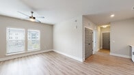 Located on Johns Island, SC, this single-floor residence at 211 Satori Way offers a clean, contemporary design with a cohesive aesthetic carried throughout every room. Light-toned luxury vinyl plank flooring runs continuously across the living spaces, complementing the neutral, warm-white walls and crisp white trim that create a bright, welcoming atmosphere.

The open living area is well-lit by a large window with blinds and is equipped with a ceiling fan, lending comfort alongside an airy, spacious feel. A hallway with stylish five-panel gray interior doors connects the living space to the rest of the home, maintaining a modern, consistent design language.

The kitchen is a functional highlight, featuring white shaker-style cabinetry with matte black hardware, light quartz countertops, a white subway tile backsplash, and a full suite of stainless steel appliances including a refrigerator, range, microwave, and dishwasher. The bathroom includes a tub-shower combination with marble-style tile surround, a vanity, and matching flooring. Bedrooms are well-proportioned with ceiling fans and generous natural light. A walk-in closet outfitted with wire shelving systems offers practical, organized storage. The overall design of this home emphasizes modern simplicity, functionality, and comfort.