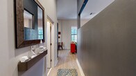 This well-appointed one-bedroom, one-bathroom residence in Baltimore, MD is a thoughtfully designed space that makes efficient use of its layout across a single floor. The entry hallway sets the tone with light wood flooring, subtle accent lighting along the baseboards, and a large decorative mirror, leading seamlessly into the main living areas.

The open-concept kitchen and living room is the heart of the home. The kitchen features dark espresso cabinetry, granite countertops, a mosaic tile backsplash, and a full suite of stainless steel appliances, including a refrigerator, range, microwave, and dishwasher. A large window floods the kitchen with natural light and offers views of the surrounding Baltimore cityscape, while a small dining area provides a practical space for meals.

The living room impresses with dramatically soaring ceilings and oversized windows that bathe the space in natural light and frame urban views. Light hardwood flooring runs throughout, complementing the warm, neutral wall tones. The bedroom area is comfortably proportioned and stylishly appointed.

The bathroom features bold warm-toned walls, dark tile flooring, a granite-topped vanity with dark cabinetry, and a tiled tub-shower combination with sliding glass doors, delivering a polished and functional finish throughout.