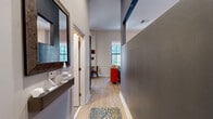 This well-appointed one-bedroom, one-bathroom residence in Baltimore, MD is a thoughtfully designed space that makes efficient use of its layout across a single floor. The entry hallway sets the tone with light wood flooring, subtle accent lighting along the baseboards, and a large decorative mirror, leading seamlessly into the main living areas.

The open-concept kitchen and living room is the heart of the home. The kitchen features dark espresso cabinetry, granite countertops, a mosaic tile backsplash, and a full suite of stainless steel appliances, including a refrigerator, range, microwave, and dishwasher. A large window floods the kitchen with natural light and offers views of the surrounding Baltimore cityscape, while a small dining area provides a practical space for meals.

The living room impresses with dramatically soaring ceilings and oversized windows that bathe the space in natural light and frame urban views. Light hardwood flooring runs throughout, complementing the warm, neutral wall tones. The bedroom area is comfortably proportioned and stylishly appointed.

The bathroom features bold warm-toned walls, dark tile flooring, a granite-topped vanity with dark cabinetry, and a tiled tub-shower combination with sliding glass doors, delivering a polished and functional finish throughout.