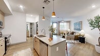 Located at 100 S 48th St in Phoenix, AZ, this well-appointed one-bedroom, one-bathroom residence offers a thoughtfully designed layout with modern finishes throughout. Wood-look flooring flows seamlessly across the entire space, creating a cohesive and warm aesthetic.

The open-concept kitchen and living area serves as the heart of the home. The kitchen is outfitted with light wood-tone cabinetry, quartz countertops, a stone tile backsplash, and stainless steel appliances including a range, over-the-range microwave, and French door refrigerator. A kitchen island with seating and pendant lighting above provides an ideal casual dining spot. The adjoining living room receives generous natural light through large windows dressed with linen drapes and blinds, and features a ceiling fan overhead.

The bedroom is a comfortable retreat, complete with its own ceiling fan, natural light from a window, and ample space for a full furniture arrangement. A dedicated closet adds practical storage.

The bathroom showcases a clean, modern design with light wood-grain cabinetry, a quartz-topped vanity, a large mirror, globe lighting, and a tub-shower combination with marble-style tile surround. White walls throughout the residence keep the atmosphere bright and open, lending the space a fresh, contemporary feel.