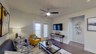 This single-floor residence offers a thoughtfully designed layout that balances style and functionality throughout. The living area serves as the heart of the space, featuring rich hardwood-style flooring, a ceiling fan with integrated lighting, and a glass-panel door that invites abundant natural light. Contemporary furnishings, bold abstract wall art, and a glass-top coffee table contribute to a modern, curated ambiance.

The kitchen is well-equipped with stainless steel appliances, including a range, microwave, and dishwasher, complemented by crisp white cabinetry and light granite countertops. The clean lines and efficient layout make it both practical and visually appealing.

The bedroom is a serene retreat, highlighted by large windows that flood the room with natural light and offer outward views. Plush carpeting and ample space create a comfortable, restful environment.

The bathroom features a full tub-shower combination with clean white tile surround, granite countertops, white cabinetry, and hardwood-style flooring, maintaining the consistent, polished aesthetic found throughout the unit.

A dedicated laundry area with an in-unit washer and built-in shelving above adds everyday convenience. Together, each space reflects a cohesive modern design with quality finishes throughout.