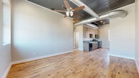 Located at 201 in Leeds, Alabama, this single-story unit blends industrial design with modern finishes to create a distinctive and functional living space. The defining architectural feature throughout is the exposed corrugated metal ceiling, which runs the length of the unit alongside visible ductwork, lending an urban, loft-inspired character to every room. Ceiling fans are installed throughout, enhancing both comfort and style.

The open main living area flows seamlessly into the kitchen, where light wood cabinetry pairs with stainless steel appliances, including a range, microwave, dishwasher, and refrigerator. Stainless steel countertops and hardwood flooring carry through the kitchen and primary living spaces, adding warmth and durability. Natural light enters through multiple windows, offering views of the surrounding area.

The bedrooms feature plush neutral carpeting, ceiling fans, and the same industrial ceiling treatment, maintaining design consistency throughout. The bathroom is finished with large-format tile flooring in a cool gray tone, a tiled tub-surround, a white vanity with a clean countertop, and a window providing natural light. The overall ambiance is modern yet inviting, balancing raw industrial elements with well-selected contemporary finishes.