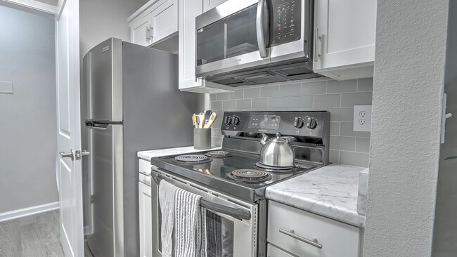 Kitchens with stylish appliances and a hip grey tile backsplash. - The Grays at Old Town