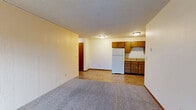 Located at 1153 Imperial Cir in Eau Claire, Wisconsin, this two-bedroom, one-bathroom unit offers a functional single-floor layout with a well-defined separation between living and sleeping spaces. The open kitchen and living area features warm honey-toned wood cabinetry, light countertops, and white appliances including a refrigerator and electric range. Durable wood-look flooring runs throughout the kitchen, while the living area transitions to plush wall-to-wall carpet. A sliding glass door in the living room opens to a balcony, bringing in natural light and outdoor access. Baseboard heating is present throughout, and a wall-mounted air conditioning unit serves the living area. Both bedrooms are carpeted and brightened by windows with neighborhood views. The primary bedroom is a comfortable size and features a double closet with built-in hanging rods, with direct access to the shared bathroom. The full bathroom includes a tub/shower combo and wood-look flooring complementing the warm wood-toned door frames and cabinetry found throughout the unit. Textured ceilings are consistent across all rooms, contributing to a cohesive, practical interior character suited for everyday living.