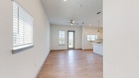 This well-designed 1-bedroom, 1-bathroom unit offers a thoughtful layout that maximizes its footprint across a single floor. The open-concept living and kitchen area forms the heart of the space, featuring light wood-style flooring, crisp white walls, and a ceiling fan that enhances airflow and comfort. A glass-paned door leads to an outdoor area, flanked by a window that fills the room with natural light and provides exterior views.

The kitchen is a standout feature, showcasing white shaker-style cabinetry, light quartz countertops, and a full suite of stainless steel appliances including a range, over-the-range microwave, dishwasher, and French door refrigerator. A kitchen island with pendant lighting above adds both workspace and visual appeal, while the layout ensures seamless flow into the living area.

The bedroom is a comfortable retreat, carpeted for warmth, with a window offering natural light and outdoor views, and a ceiling fan overhead. A dedicated closet with wire shelving provides organized storage.

The bathroom maintains the home's clean aesthetic with wood-look tile flooring, a white vanity, and a tub-shower combination featuring white subway tile surround and a window for natural ventilation. The overall ambiance throughout is bright, clean, and modern.