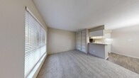 Located at Heights 2121 in the desirable Houston Heights neighborhood, this one-bedroom, one-bathroom unit offers a well-organized and functional single-story layout. The living area is generously sized, featuring soft wall-to-wall carpeting, neutral toned walls, and large windows with blinds that allow ample natural light to fill the space. A standout feature is the built-in shelving unit that elegantly separates the living area from the kitchen pass-through, providing both display and storage opportunities. The galley-style kitchen is efficiently designed with white cabinetry, light countertops, a full suite of black appliances including a range and refrigerator, and wood-look flooring that adds a warm contrast to the crisp cabinetry. The bedroom is a comfortable retreat, complete with plush carpeting, a ceiling fan with light fixture, and a window overlooking the exterior. A spacious walk-in closet with overhead rod and shelving offers excellent storage. The bathroom features wood-look flooring, a white vanity with countertop sink, and a full bathtub/shower combination. Throughout the unit, the clean, neutral palette and practical design elements create a cohesive and comfortable living environment.