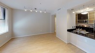 Located in the heart of Washington, DC, this single-floor residence at 733 15th St NW offers a clean, modern aesthetic throughout. The open living area is finished with light hardwood flooring that extends seamlessly across the space, lending warmth and cohesion. Track lighting overhead provides adjustable illumination, while windows fitted with horizontal blinds allow natural light to filter in, offering views of the surrounding brick streetscape.

The galley-style kitchen is thoughtfully designed with dark cabinetry, granite-look countertops, and stainless steel appliances, including a refrigerator, electric range, built-in microwave, and dishwasher. A double stainless steel sink completes the functional layout, making it well-equipped for everyday use.

The bathroom is finished in neutral cream tile, creating a calm, spa-like atmosphere. It features a glass-enclosed walk-in shower with white tile surround, a separate soaking tub, and chrome fixtures and hardware throughout.

Crisp white walls and smooth ceilings carry throughout the residence, contributing to a bright and airy feel. The overall design embraces a minimalist, contemporary style that is both practical and polished, well-suited to the vibrant urban environment of downtown Washington, DC.