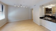 Located in the heart of Washington, DC, this single-floor residence at 733 15th St NW offers a clean, modern aesthetic throughout. The open living area is finished with light hardwood flooring that extends seamlessly across the space, lending warmth and cohesion. Track lighting overhead provides adjustable illumination, while windows fitted with horizontal blinds allow natural light to filter in, offering views of the surrounding brick streetscape.

The galley-style kitchen is thoughtfully designed with dark cabinetry, granite-look countertops, and stainless steel appliances, including a refrigerator, electric range, built-in microwave, and dishwasher. A double stainless steel sink completes the functional layout, making it well-equipped for everyday use.

The bathroom is finished in neutral cream tile, creating a calm, spa-like atmosphere. It features a glass-enclosed walk-in shower with white tile surround, a separate soaking tub, and chrome fixtures and hardware throughout.

Crisp white walls and smooth ceilings carry throughout the residence, contributing to a bright and airy feel. The overall design embraces a minimalist, contemporary style that is both practical and polished, well-suited to the vibrant urban environment of downtown Washington, DC.