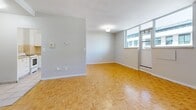 Located at 90 Eastdale Ave in Toronto's east end, this 2-bedroom, 1-bathroom unit offers a practical and well-organized layout across a single floor. Distinctive parquet wood flooring flows consistently throughout the living areas and bedrooms, lending warmth and character to the space. The combined living and dining area is generously sized, bathed in natural light through large windows that offer views of the surrounding neighbourhood, and connects to a private balcony. The kitchen features light tile flooring, white cabinetry, a tiled backsplash, and includes a full-size refrigerator and electric stove. The primary bedroom is spacious, featuring a built-in closet with bifold doors and a window with an outdoor view. The second bedroom is also well-sized with its own window and closet. In total, the unit includes three closets, providing ample storage throughout. The bathroom is finished with beige tile surround and a full bathtub. A dedicated entrance and hallway connect the rooms in a logical flow, completing this practical and comfortable unit well-suited for everyday living in Toronto.