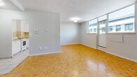 Located at 90 Eastdale Ave in Toronto's east end, this 2-bedroom, 1-bathroom unit offers a practical and well-organized layout across a single floor. Distinctive parquet wood flooring flows consistently throughout the living areas and bedrooms, lending warmth and character to the space. The combined living and dining area is generously sized, bathed in natural light through large windows that offer views of the surrounding neighbourhood, and connects to a private balcony. The kitchen features light tile flooring, white cabinetry, a tiled backsplash, and includes a full-size refrigerator and electric stove. The primary bedroom is spacious, featuring a built-in closet with bifold doors and a window with an outdoor view. The second bedroom is also well-sized with its own window and closet. In total, the unit includes three closets, providing ample storage throughout. The bathroom is finished with beige tile surround and a full bathtub. A dedicated entrance and hallway connect the rooms in a logical flow, completing this practical and comfortable unit well-suited for everyday living in Toronto.