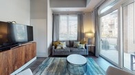 This single-floor residence is designed with a contemporary aesthetic, combining functionality and style throughout its well-defined spaces. The open-concept living area is anchored by large windows and a sliding glass door that leads to a private balcony, filling the room with natural light and providing outdoor views. Dark hardwood-style flooring, tray ceilings, and neutral gray walls contribute to a polished, modern atmosphere.

The kitchen is a standout feature, showcasing dark espresso cabinetry extending to the ceiling, granite countertops, a white subway tile backsplash, stainless steel appliances, and a substantial kitchen island with bar seating. Adjacent to the kitchen, the dining area offers an elevated ceiling and comfortable space for a full dining table.

The bedrooms are carpeted for comfort, featuring large windows with ample natural light. Both bathrooms are finished with dark vanity cabinetry, granite countertops, and light tile flooring, reflecting a consistent design language. One bathroom includes a tub and shower combination, while the other features an elongated vanity with generous counter space.

A dedicated in-unit laundry room houses a full-size washer and dryer, complemented by dark overhead cabinetry for additional storage. The overall ambiance throughout the residence is modern, cohesive, and refined.