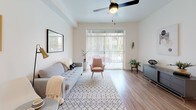 This single-floor residence showcases a cohesive modern design with warm wood-look flooring and crisp white walls throughout. The kitchen serves as a functional centerpiece, featuring dark wood-grain cabinetry, a white quartz peninsula with bar seating, stainless steel appliances including a gas range, microwave, refrigerator, and dishwasher, and pendant lighting that adds an industrial-chic touch. Recessed lighting and ample cabinetry make this space both practical and visually striking.

The living area is bright and welcoming, benefiting from natural light streaming through large sliding glass doors that open to an outdoor patio, offering views of lush greenery. A ceiling fan with a gold-toned fixture adds both style and comfort to the space.

Two bedrooms provide comfortable retreats, each featuring the same warm wood flooring and neutral walls. One bedroom benefits from a large window with horizontal blinds, allowing for natural light and outdoor views, while the other offers a quieter, more private atmosphere.

The bathroom maintains the unit's consistent design language, with a dark wood-grain vanity, white quartz countertop, a large mirror, and wood-look flooring, creating a clean and modern aesthetic throughout.