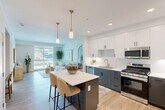 Located at 3100 Martin in Irvine, CA, this thoughtfully designed one-bedroom, one-bathroom residence offers a clean, contemporary aesthetic throughout its efficiently utilized single-floor layout. The open-concept living and kitchen area is anchored by light-toned luxury vinyl plank flooring and large windows that invite generous natural light and outdoor views, creating a bright and airy atmosphere. The kitchen features a two-tone design with crisp white upper cabinetry and charcoal lower cabinets, white quartz countertops, stainless steel appliances including a gas range, built-in microwave, dishwasher, and refrigerator, along with a pantry for additional storage. The living area flows seamlessly, offering a versatile space ideal for both relaxing and dining. The bedroom is a serene retreat with soft carpeting, a ceiling fan, and windows that bring in natural light. It connects directly to a spacious walk-in closet with built-in shelving and hanging rods. The full bathroom features wood-toned cabinetry, a white quartz vanity, a soaking tub, and wood-look flooring. Additional highlights include three closets for storage and a dedicated in-unit laundry area, rounding out this well-appointed Irvine residence.