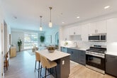 Located at 3100 Martin in Irvine, CA, this thoughtfully designed one-bedroom, one-bathroom residence offers a clean, contemporary aesthetic throughout its efficiently utilized single-floor layout. The open-concept living and kitchen area is anchored by light-toned luxury vinyl plank flooring and large windows that invite generous natural light and outdoor views, creating a bright and airy atmosphere. The kitchen features a two-tone design with crisp white upper cabinetry and charcoal lower cabinets, white quartz countertops, stainless steel appliances including a gas range, built-in microwave, dishwasher, and refrigerator, along with a pantry for additional storage. The living area flows seamlessly, offering a versatile space ideal for both relaxing and dining. The bedroom is a serene retreat with soft carpeting, a ceiling fan, and windows that bring in natural light. It connects directly to a spacious walk-in closet with built-in shelving and hanging rods. The full bathroom features wood-toned cabinetry, a white quartz vanity, a soaking tub, and wood-look flooring. Additional highlights include three closets for storage and a dedicated in-unit laundry area, rounding out this well-appointed Irvine residence.
