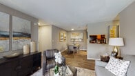 Located at 3750 Peachtree Industrial Blvd in Duluth, Georgia, this single-floor residence offers a thoughtfully designed layout with a cohesive, neutral color palette of warm grays and taupe tones throughout. The open-concept living area features wood-look flooring, large windows that invite natural light, and a seamless flow into a dedicated dining space adorned with decorative framed artwork. The kitchen is efficiently arranged with warm wood cabinetry, dark granite-style countertops, a tile backsplash, and a full suite of black appliances including a refrigerator, range, microwave, and dishwasher. A pass-through connects the kitchen to the living and dining areas, enhancing the open feel. A laundry area is conveniently accessible from the kitchen. The primary bedroom is generously sized with plush carpeting, a sliding glass door leading to a private balcony, and ample natural light. The second bedroom also features carpet flooring and a large window with outdoor views. Two bathrooms serve the residence — one with a tub-shower combination and warm wood vanity cabinetry, and a second with a shower and wood-look flooring. Textured ceilings and recessed lighting are consistent throughout, contributing to a clean and comfortable living environment.