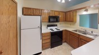 This single-floor, two-bedroom, one-bathroom residence offers a practical and comfortable layout spanning a generous footprint. The kitchen is equipped with classic oak cabinetry providing ample storage, white appliances including a full-size refrigerator and electric range, an over-the-range microwave, and light countertops — all set on tile flooring beneath a ceiling light fixture. The living area features plush wall-to-wall carpeting, neutral cream-toned walls, and a sliding glass door that opens to a private balcony overlooking lush greenery, allowing natural light to fill the room. The primary bedroom is spacious with carpeted floors, a ceiling fan with light kit, and a built-in double-door closet offering generous storage. A second bedroom provides comfortable proportions, carpeted flooring, and a wood-framed window with wooded views. Both bedrooms feature neutral tones and standard trim work consistent throughout the home. The full bathroom includes a tub-shower combination, tile flooring, and clean, functional fixtures. The overall ambiance of this residence is warm and understated, with wood-accented doors and trim tying the spaces together cohesively.