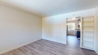 Located at 1158 Sunnyvale-Saratoga Rd in Sunnyvale, CA, this single-floor unit offers a clean, functional layout ideal for comfortable everyday living. Throughout the space, light-toned laminate wood flooring provides a cohesive and low-maintenance surface underfoot, complemented by crisp white walls that maximize the sense of brightness and openness.

The living area is generously proportioned, featuring built-in shelving along one wall and a wall-mounted heating unit, offering both practicality and a tidy aesthetic. Natural light filters in from windows facing greenery, creating a calm and inviting atmosphere.

The kitchen is efficiently designed and well-equipped, featuring dark lower cabinetry contrasted with lighter upper cabinets, stone-look countertops, a stainless steel sink, a white electric coil range, and a full-size refrigerator. A window above the sink brings in natural light and views of surrounding foliage, making the kitchen feel airy despite its compact footprint.

A dedicated bedroom area provides a quiet retreat, with clean walls and ample floor space. The bathroom is finished with neutral tile work, a white vanity with under-sink storage, and a tub and shower combination enclosed by sliding frosted glass doors, with a small window allowing natural ventilation. The overall ambiance of the unit is clean, practical, and move-in ready.