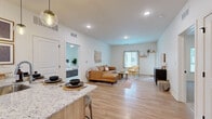 Located at 7510 N Oak Trafficway in Gladstone, MO, this 2-bedroom, 2-bathroom single-floor residence offers a well-designed open-concept layout with a clean, modern aesthetic throughout. Light wood-tone flooring flows seamlessly through the main living areas, complemented by crisp white walls and recessed lighting that create a bright, airy atmosphere.

The kitchen is a standout feature, boasting granite countertops, white upper cabinetry paired with natural wood lower cabinets, and a full suite of stainless steel appliances. A large kitchen island with seating for multiple guests provides both functionality and a natural gathering point that connects effortlessly to the open living room.

The living room is generously proportioned, with windows allowing natural light to fill the space and a front entry door offering convenient access. The primary bedroom is a comfortable retreat, featuring plush carpeting, a ceiling fan, natural light from a large window, and direct access to a private bathroom and a spacious walk-in closet with built-in shelving. The second bedroom maintains the same warm, neutral character. Both bathrooms are finished with wood-tone vanities and granite countertops, continuing the cohesive design language found throughout this well-appointed home.
