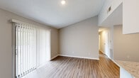 Located at 1 Aspen Dr in Greensboro, NC, this 2-bedroom, 2-bathroom residence offers a thoughtfully designed single-floor layout with modern finishes throughout. The open-concept living and kitchen area anchors the home, featuring light wood-look vinyl plank flooring, neutral warm-toned walls, and a textured ceiling. Vertical blinds along a large sliding door allow for adjustable natural light in the living space. The kitchen is a standout, boasting granite countertops, a peninsula with an undermount sink, gray shaker-style cabinetry, subway tile backsplash, stainless steel appliances, and track lighting overhead. Both bedrooms are carpeted and filled with natural light from large windows with blinds. The primary bedroom offers a comfortable, well-sized layout, while the secondary bedroom includes built-in shelving, a desk, and a closet — ideal as a functional workspace or guest room. The bathrooms are finished with granite vanity tops, undermount sinks, and tile shower-tub combinations. A dedicated laundry area houses a full-size washer and dryer with overhead shelving for storage. This residence combines practical functionality with clean, contemporary design throughout.