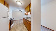 This single-floor unit offers a practical and well-organized layout designed for comfortable everyday living. The kitchen serves as a functional centerpiece, featuring warm honey-toned oak cabinetry with ample upper and lower storage, granite-look countertops, a double-basin sink, and a full suite of appliances including an electric range, refrigerator, and range hood. Tile flooring runs throughout the kitchen, providing a durable and easy-to-maintain surface. A ceiling fan overhead adds comfort to the adjacent dining or living area, which transitions seamlessly from the kitchen space.

The living area is generously proportioned, finished with soft carpeting and neutral walls that create a clean, versatile backdrop. A wall-mounted air conditioning unit and baseboard heating ensure year-round climate control. Natural light filters in through windows that frame views of the surrounding neighborhood.

The bedroom continues the carpeted flooring and offers a window with natural daylight, wood-trimmed details, and baseboard heating for added warmth. An entry area transitions between tiled and carpeted surfaces, offering a convenient threshold space.

The bathroom is neatly appointed with a single-vanity featuring a white countertop and mirrored medicine cabinet, classic mosaic tile flooring, and a full tub-shower combination with white tile surround. The overall aesthetic throughout the unit is clean, understated, and move-in ready.