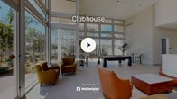 Located at 25150 Jefferson Ave in Murrieta, CA, this single-floor community clubhouse offers a generously sized, thoughtfully designed gathering space defined by contemporary architecture and an abundance of natural light. Soaring double-height ceilings and expansive floor-to-ceiling glass walls are central to the design, creating an airy, open atmosphere with unobstructed views of the surrounding outdoor courtyard and landscaping.

The entrance welcomes visitors into a spacious lobby-style living area furnished with stylish seating arrangements, including plush sofas, leather accent chairs in warm orange tones, and vibrant potted palms that bring life and color to the neutral palette. A second living area features a full-size billiards table, additional lounge seating, and the same dramatic glazed walls that flood the room with Southern California sunshine.

A striking bar and lounge counter runs along one side of the space, topped with a sleek surface and backed by a richly veined marble wall. Warm wood slat ceiling panels and rich walnut cabinetry add an elegant contrast to the light limestone-tiled floors throughout. A separate catering or prep area includes additional wood cabinetry and stone countertops. Two well-maintained restrooms, finished with dark tile wainscoting and stainless steel fixtures, complete this polished and functional community space.