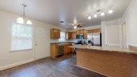 Located at 1 Hampstead Heath Way in Hampton, Virginia, this two-floor home offers a functional and well-maintained layout across both levels. The kitchen serves as a central highlight, featuring warm oak cabinetry, dark granite-style countertops, and a full suite of stainless steel appliances including a refrigerator with ice maker, electric range, built-in microwave, and dishwasher. A peninsula provides additional counter space, while dark hardwood-style flooring and a ceiling fan complete the room. Natural light flows in through multiple windows, and a pendant chandelier adds a complementary accent near the dining area. The bedrooms are finished with plush carpeting and neutral tones, providing a comfortable and quiet retreat. One bedroom includes a built-in closet with shelving, while another features a ceiling fan and a bright window with outdoor views. The bathrooms include a full bath with a tub-shower combination and subway tile accents, as well as a half bath finished with stone-look tile flooring and white subway tile wainscoting. A dedicated laundry room houses a full-size washer and dryer, adding everyday convenience. Throughout the home, a consistent palette of neutral walls and clean finishes creates a cohesive and move-in-ready environment.