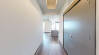 This well-designed single-floor residence offers a comfortable living experience with its 1250 square feet of thoughtfully allocated space. The home boasts four bedrooms, including a spacious primary bedroom measuring 160 square feet, providing ample room for relaxation and personal comfort. With three bathrooms, the property ensures convenience for family members and guests alike. The layout includes a hallway for easy navigation, two closets for storage solutions, and a combined kitchen and living room area, ideal for modern, open-concept living. The interior, as seen in the image, features clean, white walls that create a bright and airy atmosphere. The flooring appears to be high-quality, durable laminate in a warm, neutral tone, adding both style and practicality to the space. Recessed lighting in the ceiling contributes to the overall modern aesthetic while providing effective illumination. A notable feature is the sliding barn door visible in the image, adding a touch of contemporary design to the home's interior. This residence combines functionality with aesthetic appeal, offering a balanced living environment for its occupants.