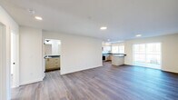 Located at 1707 Element Lane in Sandpoint, Idaho, this thoughtfully designed 2-bedroom, 2-bathroom residence offers a clean, modern aesthetic across a single floor. The open-concept living and kitchen area is anchored by warm hardwood-style flooring, recessed lighting, and crisp white walls that create a bright, welcoming atmosphere. The well-appointed kitchen is a standout feature, showcasing light wood cabinetry with sleek black hardware, dark granite-style countertops, stainless steel appliances including a range, microwave, dishwasher, and refrigerator, and a peninsula that provides additional prep and serving space. Natural light filters in through multiple windows, enhancing the open feel of the main living area. The generously sized primary bedroom features large windows, a wall-unit climate control system, and sun-drenched hardwood-style floors. Both bedrooms include closets, with one featuring sliding double doors. The primary bathroom is equipped with a dual-sink vanity, light wood cabinetry, dark countertops, and a full tub-shower combination. The second bathroom also offers a tub-shower setup. Throughout the residence, the consistent use of neutral tones, modern fixtures, and quality materials reflects a cohesive and contemporary design sensibility.