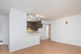 Located at 1605 13th Ave S in Birmingham, Alabama, this single-floor unit offers a well-organized layout that balances open communal areas with defined private spaces. Light-toned hardwood-style flooring runs throughout the main living and bedroom areas, creating a cohesive and clean aesthetic across the unit.

The living area is generously proportioned, benefiting from large windows fitted with horizontal blinds that admit ample natural light. A wall sconce provides supplemental ambient lighting, and the open layout connects seamlessly to the kitchen via a peninsula featuring a granite countertop—an ideal surface for casual dining or food preparation.

The kitchen is well-equipped with taupe-toned cabinetry, a subway tile backsplash, and black appliances including a refrigerator, range, built-in microwave, and dishwasher. Track lighting illuminates the workspace, and tile flooring provides a practical surface in this area.

The bedrooms continue the hardwood-style flooring and are finished with white walls and standard overhead lighting. One bedroom features a large window that fills the room with natural light, while another includes a wall-mounted heater unit.

The bathroom presents a clean, functional design with white square tile on the walls and floor, a toilet, and a full bathtub with shower surround.