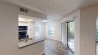 Located at 1752 Hidden Bluff Trail in Arlington, Texas, this single-story unit offers a well-organized layout with consistent wood-style flooring and a neutral color palette throughout. The open-concept living and dining area is bright and welcoming, benefiting from multiple windows fitted with blinds and a glass sliding door that leads to a private balcony overlooking lush greenery. A ceiling fan with integrated lighting adds functionality to the living space, which also features a textured ceiling.

The galley-style kitchen is efficiently designed with white cabinetry, gray countertops, a stainless steel sink, and a full suite of black appliances including a refrigerator, electric range, microwave, and dishwasher. A peninsula counter connects the kitchen to the living area, enhancing the open feel.

The bedrooms are comfortably sized, with one featuring rich, dark wood-style flooring and a textured ceiling, while another offers a lighter hardwood-style floor finish. The bathroom includes a vanity with gray countertops, an undermount sink, brushed nickel fixtures, and a framed mirror with contemporary lighting above. Clean white walls and consistent finishes give the entire unit a cohesive, move-in-ready appearance.