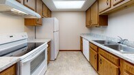 Located at 400 E Alexandersville-Bellbrook Rd in Centerville, Ohio, this single-floor unit offers a practical and well-organized layout across several interconnected living spaces. The living area is generously sized, finished with neutral-toned carpet and featuring a sliding glass door with vertical blinds that opens to outdoor views, alongside an additional window that brings in natural light. A wall-mounted air conditioning unit and baseboard heating provide year-round climate control throughout the unit.

The galley-style kitchen is efficiently designed with warm oak cabinetry lining both sides, light granite-look countertops, a skylight overhead, and a full suite of white appliances including an electric range, refrigerator, and dishwasher. The tile flooring adds durability to this functional cooking space.

The bedrooms are carpeted and well-lit, with multiple windows overlooking the surrounding greenery. One bedroom notably features multiple closets with sliding wood-panel doors, offering exceptional storage capacity. Additional rooms provide quiet, versatile spaces suitable for various uses.

The bathroom is finished with classic white tile wainscoting, a patterned arabesque tile floor in soft teal tones, a vanity with under-cabinet storage, and a full bathtub with a shower curtain. Grab bars are also present, adding accessibility-conscious detail to the space.