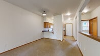 Located at 801 Blueberry Ln in Bellingham, Washington, this two-story residence offers five bedrooms and two bathrooms across a thoughtfully laid-out floor plan. The main level features an open-concept kitchen and living room area, where warm-toned wood cabinetry pairs with dark countertops and a breakfast bar peninsula — ideal for casual dining. The living area is highlighted by a tile-surround fireplace, adding a cozy focal point to the carpeted space. A dedicated laundry room includes full-size Maytag washer and dryer units with overhead shelving, while a separate kitchen provides additional functionality with ample cabinetry and a window overlooking the exterior. The upper level houses the bedrooms, all finished with plush carpet and neutral walls. Bedrooms receive natural light through sliding-pane windows with views of surrounding greenery. The shared bathroom features a double-sink vanity with wood-framed mirrors, a tub-shower combo, and tile flooring. Throughout the home, warm wood trim accents doorframes and baseboards, lending a consistent and cohesive aesthetic. The layout is practical and well-proportioned, offering comfortable living across both floors.