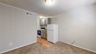 This single-floor 1-bedroom, 1-bathroom unit offers a straightforward and functional layout suited for comfortable everyday living. The living area greets you at the entrance, featuring carpet flooring, neutral gray walls with vertical paneling accents, and a textured ceiling. A window allows natural light to brighten the space. The kitchen is efficiently designed with warm hardwood-style flooring, gray cabinetry, a dark countertop, a built-in electric range, and a full-size refrigerator. A single-basin sink completes the kitchen setup, with direct access to the rest of the unit. The bedroom is a comfortable, carpeted retreat with vertical panel wall detailing, a window that lets in natural light, and a reach-in closet providing ample storage. The bathroom features hardwood-style flooring, a pedestal sink with a mirrored medicine cabinet above, an overhead storage cabinet, a toilet, and a walk-in shower stall. Throughout the unit, consistent neutral tones and practical finishes create a cohesive and low-maintenance living environment. The compact, efficient floor plan makes excellent use of the available space, offering all essential amenities in a well-organized arrangement.