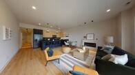 Located at 290 Stonington Dr in Bloomingdale, Illinois, this contemporary single-floor residence showcases a thoughtfully designed open-concept layout that seamlessly connects the main living areas. Light hardwood flooring runs throughout, creating a warm, cohesive aesthetic that complements the modern interior design.

The expansive living area is anchored by a sleek linear fireplace set against a clean white surround, offering an inviting focal point. Large windows allow generous natural light to fill the space while providing views of the surrounding landscape. The living area flows naturally into a dedicated dining space, ideal for entertaining.

The kitchen is a standout feature, boasting dark matte countertops and island with bar seating, light wood upper cabinetry, a dark backsplash, and stainless steel appliances. Stylish pendant lighting adds visual interest overhead, while open shelving provides both function and display space.

The bathrooms are finished to a high standard — one features a vessel sink on a floating wood-topped vanity with a round mirror and dramatic dark marble tile shower surround, while another presents a wall-mounted white vanity with a large frameless mirror and sage-toned walls.

Bedrooms are bright and airy, with large floor-to-ceiling windows and access to walk-in closet space, completing this polished, modern home.