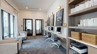 Located at 1124 Shoreview Circle in Casselberry, Florida, this single-story community amenity space combines sophisticated design with practical functionality. The grand lounge area anchors the space with soaring ceilings, coffered wood-accented details, and large-format light tile flooring. Floor-to-ceiling black-framed glass walls flood the interior with natural light and provide direct views of the outdoor patio and lush Florida palm landscaping beyond.

The open lounge is furnished with a curated arrangement of wooden accent chairs, plush seating, and layered area rugs, creating an inviting social atmosphere. Bold, oversized artwork adds character throughout, while elegant wall sconces and pendant lighting contribute a refined ambiance.

A dedicated co-working zone features a long built-in desk with multiple workstations, mesh ergonomic chairs, and integrated shelving with warm wood tones. Wall-mounted art and gold sconce lighting elevate the workspace aesthetic. Adjacent to this area are private, glass-fronted office suites, each enclosed by dark-framed French doors. These individual rooms offer focused work environments, equipped with desks, task chairs, and curated artwork, with carpet flooring providing acoustic comfort. Together, the spaces deliver a seamless blend of community, comfort, and modern design.