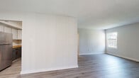 Located at 5840 Newtown Arch in Virginia Beach, Virginia, this single-floor unit presents a clean, updated interior with a cohesive neutral color palette throughout. The open living areas are finished with durable wood-look luxury vinyl flooring in a cool gray tone, lending a modern, low-maintenance feel to the space. A sliding glass door fitted with vertical blinds allows natural light to fill the main living area while providing outdoor access.

The kitchen has been thoughtfully updated with gray shaker-style cabinetry accented by gold hardware, warm butcher block countertops, and a full suite of stainless steel appliances, including a gas range, over-the-range microwave, and dishwasher. The layout connects efficiently to the living space, making it well-suited for everyday use.

The bedrooms feature plush gray carpeting and offer generous closet space, including sliding and hinged closet doors with built-in rods for organization. Multiple windows in the bedrooms invite natural light and outdoor views of the surrounding greenery.

The bathrooms are finished with wood-look vinyl flooring, white tiled tub-shower combinations, and matte black fixtures and hardware, adding a contemporary contrast to the bright, clean surroundings. The overall design is cohesive, practical, and well-maintained throughout.