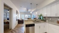 Located at 465 S 700 E in Salt Lake City, Utah, this one-bedroom, one-bathroom unit offers a thoughtfully designed single-floor layout with modern finishes throughout. The entryway opens into a kitchen and living area, where wood-style flooring, clean white walls, and abundant natural light create a bright and welcoming atmosphere. The kitchen is well-appointed with crisp white shaker cabinetry, granite-style countertops, a tile backsplash, and a full suite of stainless steel appliances including a refrigerator, range, and over-the-range microwave. The living room features plush carpeting, a large window with exterior views, and a tray ceiling detail that adds architectural dimension to the space. The spacious primary bedroom continues the carpeted flooring and features a tray ceiling with a ceiling fan, a window for natural light, and convenient access to a closet that houses an in-unit stacked washer and dryer. The bathroom is finished with a white vanity, granite-topped counters, a large mirror, wood-style flooring, and a tub-shower combination. A hallway connects all rooms efficiently, completing the functional and cohesive floor plan.
