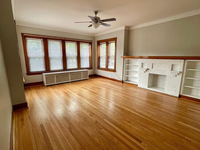 Sala de estar con estanterías empotradas y chimenea ornamental. - 5336 W Dakin St