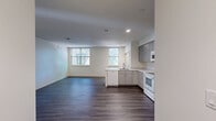 Located at 1 Frost Terrace in Cambridge, MA, this thoughtfully designed 2-bedroom, 1-bathroom residence offers a clean, modern aesthetic across a single floor. The interior is unified by durable wood-look plank flooring and a crisp white color palette that creates a bright, cohesive atmosphere throughout.

The kitchen is a functional highlight of the home, featuring gray flat-front cabinetry with ample upper and lower storage, white countertops, and a full suite of white appliances including a refrigerator, electric range, and over-the-range microwave. A peninsula with an integrated sink provides additional workspace and a natural division between the kitchen and living area.

The living area is open and well-lit, with a large window allowing natural light to fill the space. Both bedrooms are generously proportioned, each featuring wood-look flooring, neutral walls, and windows that invite outdoor views and natural light. The primary bedroom includes a double-door closet, while the second bedroom also benefits from multiple windows with leafy outdoor views.

The bathroom is clean and efficiently designed, featuring a full tub-shower combination with built-in shelving. A hallway connects all rooms, contributing to the home's practical and navigable layout. Overall, this residence offers a modern, move-in-ready living environment in a prime Cambridge location.