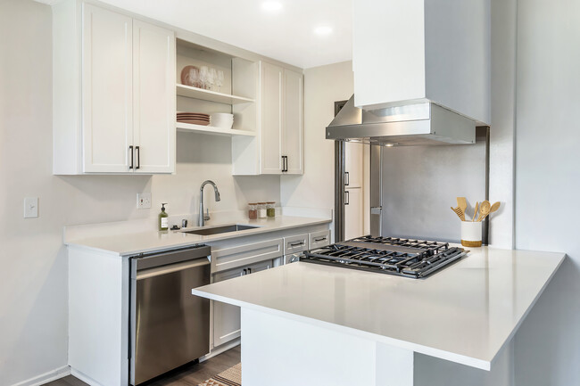 Cocina renovada del Paquete I con electrodomésticos de acero inoxidable, encimeras de cuarzo blanco, gabinetes blancos y pisos de superficie dura (hogares seleccionados) - AVA Burbank