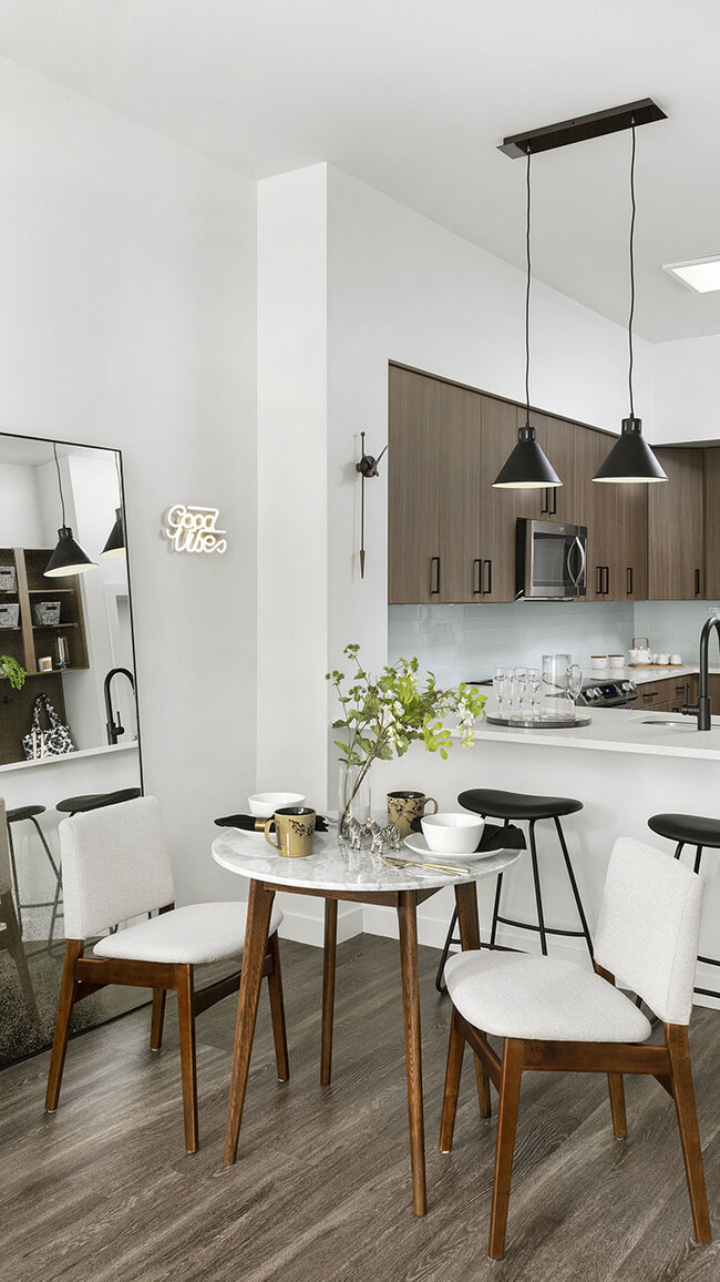 Cocina del apartamento con electrodomésticos de acero inoxidable, encimera de cuarzo y piso de madera. - Griffis Cherry Creek North