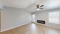 Located at 6401 Hulen Bend Blvd in Fort Worth, TX, this one-bedroom, one-bathroom residence offers a well-designed single-level layout with a clean, modern aesthetic. The living room is an immediate standout, featuring vaulted ceilings that lend an airy, open feel to the space. A sleek, wall-mounted linear fireplace serves as a focal point, complemented by warm wood-look flooring, soft gray walls, and a ceiling fan with integrated lighting. Natural light filters in through a glass-paned door that opens to the private patio. The combined dining and kitchen area showcases a galley-style layout with white shaker cabinetry, light quartz countertops, a gray subway tile backsplash, black appliances, and track lighting overhead. The bedroom features plush carpet, vaulted ceilings, a ceiling fan, and two closets providing ample storage. The bathroom is finished with a floating white vanity, quartz countertop, framed mirror, and brushed nickel fixtures, all set against wood-look flooring consistent with the rest of the home. A hallway connects the rooms efficiently, and a private patio rounds out the layout, offering a dedicated outdoor space.