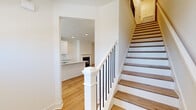 Located at 1801 Hamilton Rd in LaGrange, Georgia, this two-story home offers a thoughtfully designed layout across two floors. The main level features a welcoming living area centered around a sleek fireplace and ceiling fan, with warm wood-look flooring that flows throughout. The kitchen is a standout space, showcasing white shaker-style cabinetry, granite countertops, stainless steel appliances, and a generous island with an integrated sink — complemented by a walk-in pantry. A conveniently located bathroom on the main floor features a pedestal sink and clean, bright finishes. An elegantly designed staircase with wood treads, white newel posts, and black balusters connects the floors. Upstairs, the more expansive floor hosts three bedrooms, including a spacious primary suite, along with two additional bathrooms and hallway access. Each bedroom includes closet storage, with wire shelving systems providing practical organization. The walk-in closet offers multi-rod hanging space. The attached garage provides secure vehicle storage with a double-wide door and concrete flooring. Throughout the home, consistent light wood flooring, recessed lighting, and crisp white walls create a clean, modern aesthetic.