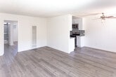Located at 6300 Lankershim Blvd in the North Hollywood neighborhood of Los Angeles, Unit 212 is a well-appointed single-floor residence designed with a clean, modern aesthetic. Light-toned wood-style flooring runs throughout the unit, complementing the crisp white walls and creating a bright, cohesive atmosphere.

The kitchen is a standout feature, outfitted with white shaker cabinetry, stone-look countertops, and a striking mosaic tile backsplash in a dark blue and grey palette. Stainless steel appliances include a gas range, over-the-range microwave, refrigerator, and dishwasher. Track lighting illuminates the workspace, and a peninsula counter connects the kitchen to the living area, offering additional prep space and a natural dividing element.

The open living area is bathed in natural light from multiple windows fitted with vertical blinds. A ceiling fan adds both function and character, while a wall-mounted air conditioning unit provides climate control. The bedroom is generously sized with a large window overlooking the exterior and a sliding closet door.

The bathroom features white cabinetry, a stone-look countertop vanity, an undermount sink, and a wide mirror with a side panel for extended reflection. The overall layout is practical and efficient, with well-defined spaces that flow seamlessly from one to the next.