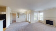 Located at 1201 Dulles Ave in Stafford, Texas, this single-story residence offers a well-designed, open layout with a variety of functional and comfortable spaces throughout. The main living area is generously sized, featuring plush carpeting, crown molding, and multiple windows with blinds that allow abundant natural light to fill the room. A tile-surround fireplace serves as a focal point, while a sliding glass door opens to an outdoor balcony, providing pleasant exterior views. An elegant chandelier illuminates the adjacent dining area, which connects seamlessly to the living space through a mirrored pass-through wall. The kitchen is efficiently designed with white cabinetry, light granite-style countertops, hardwood flooring, and black appliances including a range, over-the-range microwave, and dishwasher. A breakfast bar adds additional utility. The bedrooms are carpeted and well-proportioned; one features a built-in shelving nook and closet, while another includes a ceiling fan and an adjoining built-in desk area with a window. The primary bathroom offers dual sinks set in granite-style countertops, white cabinetry, hardwood flooring, and a tub-shower combination. A secondary bathroom mirrors the clean aesthetic with a single vanity, granite countertop, and a tub-shower unit.